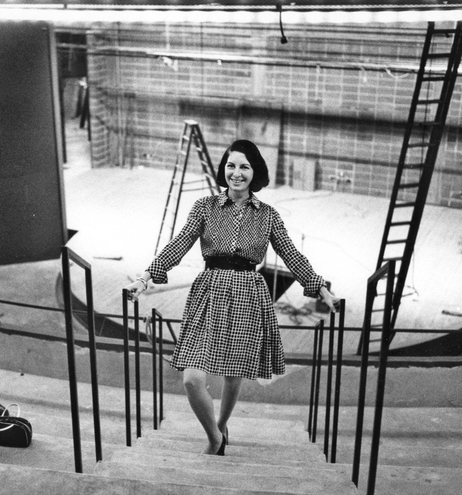Zelda Fichandler smiling on the steps of an Arena Stage theatre under construction